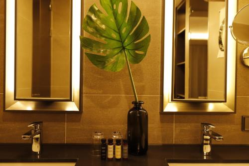 a black vase with a plant in it on a bathroom counter at Best Western Plus Jeonju in Jeonju