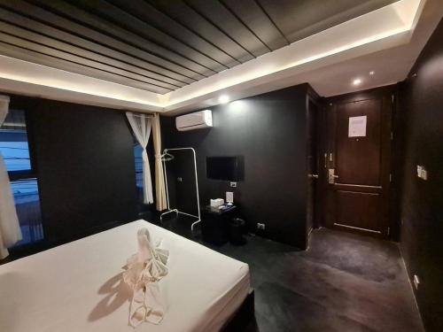 a bedroom with a white bed and a tv at Trat 101 Hotel - SHA Certified in Trat