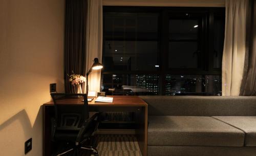 a room with a desk and a couch and a window at Best Western Plus Jeonju in Jeonju