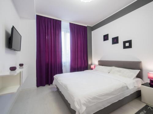 ママイア・ノルドにあるSun & Sea Apartament Mamaia Nordのベッドルーム(白いベッド1台、紫色のカーテン付)