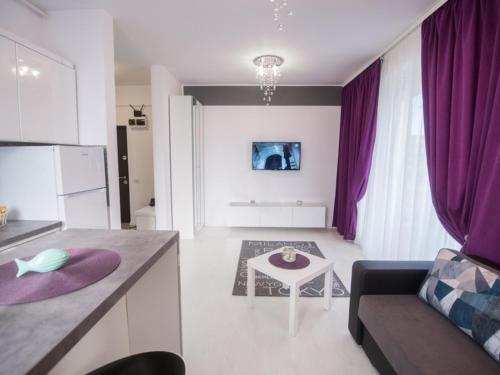 ママイア・ノルドにあるSun & Sea Apartament Mamaia Nordのキッチン、リビングルーム(紫色のカーテン、ソファ付)