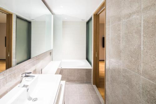 a bathroom with a sink and a bath tub at Ibis Ambassador Suwon in Suwon
