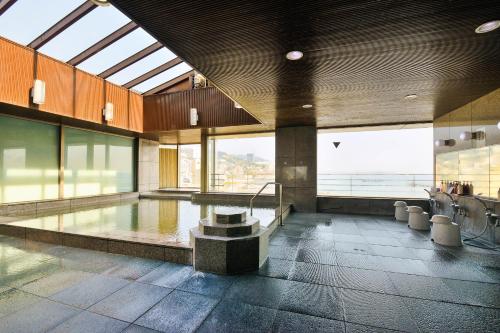 a swimming pool in a building with a large window at Hotel Sunmi Club in Atami