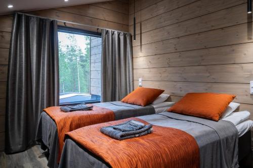 two beds in a room with wooden walls at Premium Resorts Vierumäki in Vierumäki