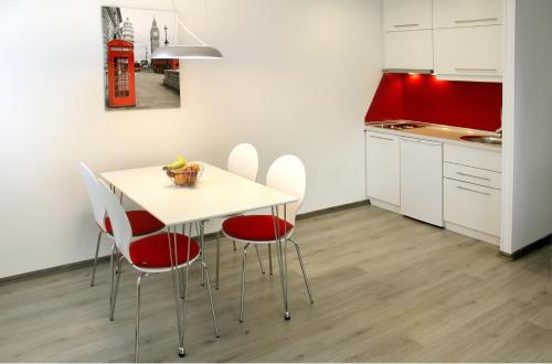 a kitchen with a white table and red chairs at Modern City Apartments in Sarajevo