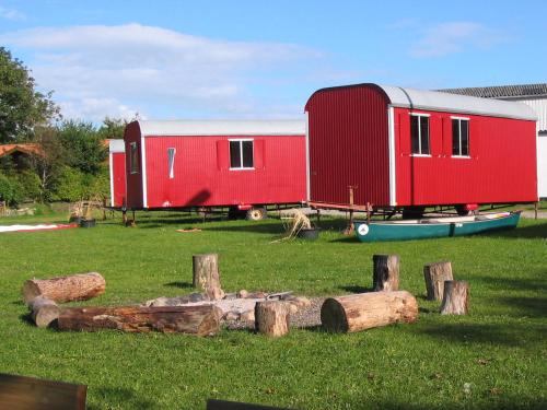 a red trailer sitting in a field with logs at Treene Camp Horn in Esperstoft