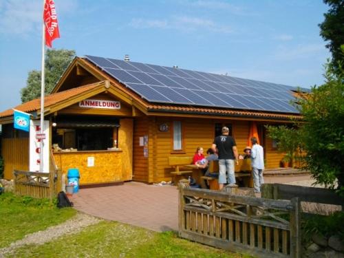 Esperstoft的住宿－Treene Camp Horn，一群人站在一座拥有太阳能电池板的建筑外