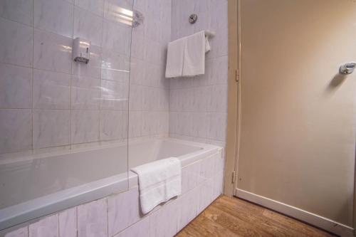 La salle de bains blanche est pourvue d'une baignoire et d'une douche. dans l'établissement Topaz Hotel, à San Pawl il-Baħar