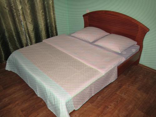 a bed with a wooden head board and white sheets at Комфортная 2-комнатная Новопречистенская 1, Три раздельных двуспальных места in Cherkasy