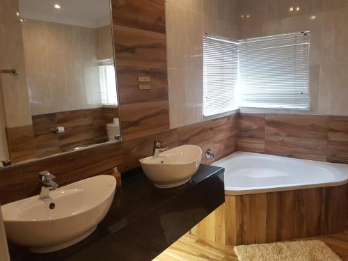 a bathroom with a tub and two sinks and a tub and a bath tub at Cornerstone Guest Lodge in Pretoria