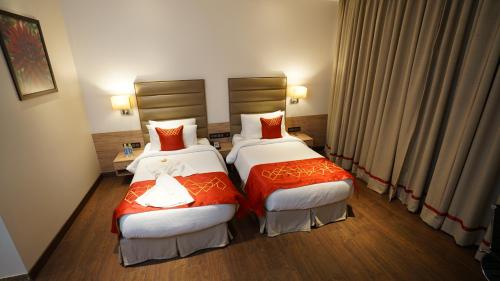 a hotel room with two beds with red pillows at Ramada by Wyndham Aligarh GT Road in Alīgarh