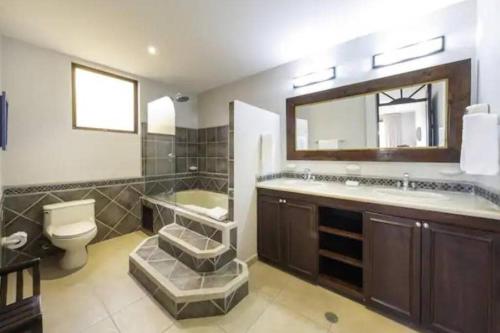 La salle de bains est pourvue d'un lavabo, de toilettes et d'un miroir. dans l'établissement 777J Beachfront Luxury Condo 3 BR/2.5BA Near SJO - Jaco Beach, à Jacó