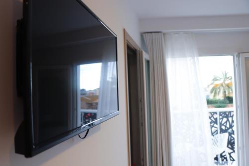 a flat screen tv hanging on a wall next to a window at Hotel Sunna Benicassim in Benicàssim