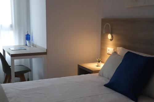 a bedroom with a bed and a desk with a blue pillow at Hotel Sunna Benicassim in Benicàssim
