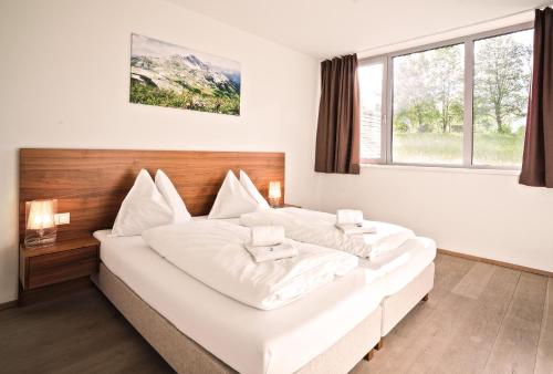 a large white bed in a room with a window at Tauernresidence Radstadt by ALPS RESORTS in Radstadt