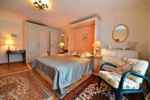ein Schlafzimmer mit einem Bett, einem Stuhl und einem Spiegel in der Unterkunft Le Lierre B&B in Genolier