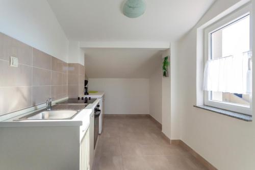 eine weiße Küche mit einem Waschbecken und einem Fenster in der Unterkunft Apartments Katarina B in Sveti Vid-Miholjice