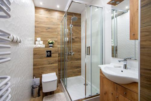 ein Bad mit einer Dusche und einem Waschbecken in der Unterkunft Apartamenty w Centrum - Zakopane in Zakopane