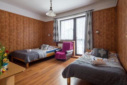 Zimmer mit 2 Betten, einem Stuhl und einem Fenster in der Unterkunft Apartamenty w Centrum - Zakopane in Zakopane