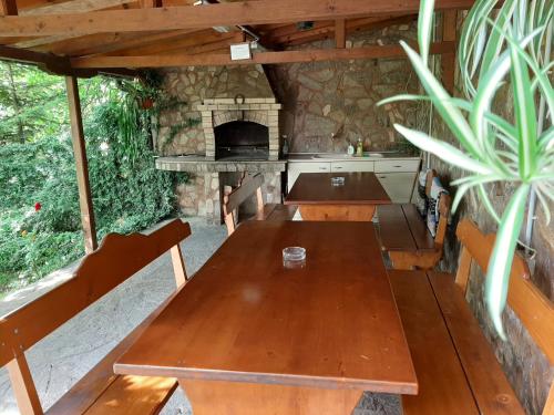uma cozinha exterior com uma mesa de madeira e uma lareira em Villa Prolet em General-Kantardzhievo