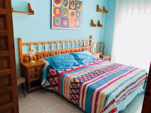 um quarto com uma cama de madeira e um cobertor colorido em BUNGALOW DUPLEX Peñismar II em Peníscola