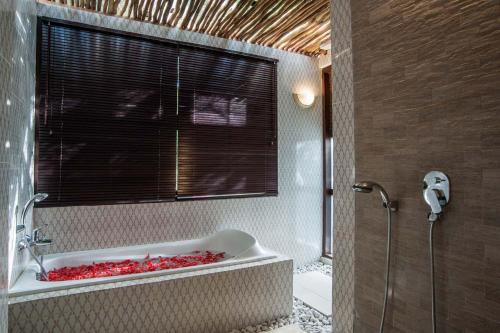 a bathroom with a bath tub with a window at Villa Matha Ubud - Renewal in Ubud