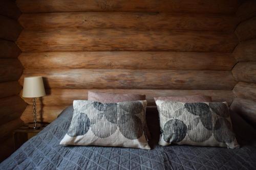 a bedroom with a wooden wall with a bed with two pillows at Loma-Autio Apaja in Puumala