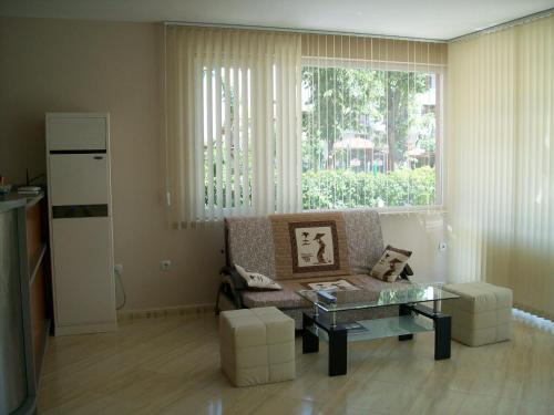 ein Wohnzimmer mit einem Sofa, einem Tisch und einem Fenster in der Unterkunft Guest House Donchevi in Primorsko