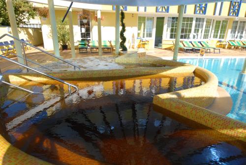 a swimming pool with a fountain in front of a building at Hotel Rudolf in Hajdúszoboszló
