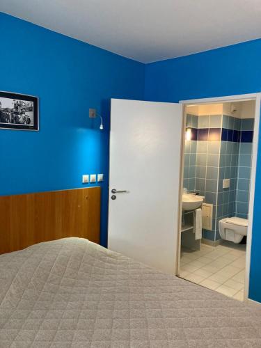 a blue bedroom with a bed and a bathroom at L'ETAPE DE SANTENAY in Santenay