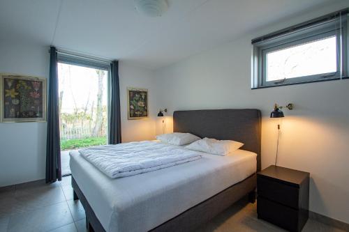 een slaapkamer met een bed met 2 lampen en een raam bij Sandepark 171 - Groote Keeten in Callantsoog