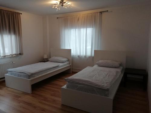 two beds in a room with two windows at Apartment AMS in Oststeinbek