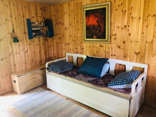 a bed in a room with a wooden wall at Tiny hut in the forest overlooking the river in Avesta