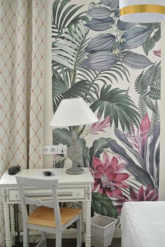 a lamp on a white table with a tropical wallpaper at Logis Hôtel Louise de Savoie in Blois