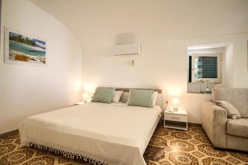 una camera bianca con un letto e una sedia di Alfa Est a Patù