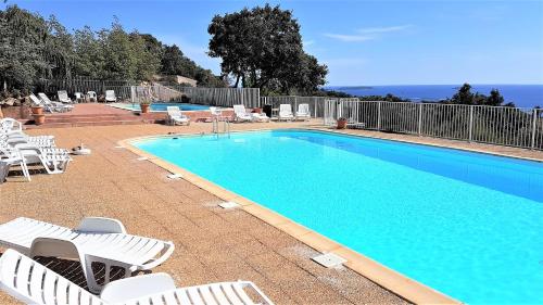 une piscine avec des chaises longues blanches et une piscine dans l'établissement Maison 4 pièces, vue panoramique, piscine, climatisation, près de Palombaggia, à Porto-Vecchio