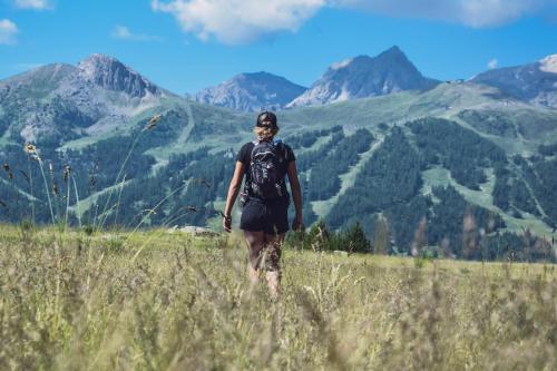 a person standing in a field with mountains in the background at SOWELL HOTELS Le Parc & Spa in Briançon