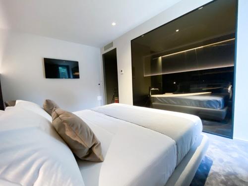un letto bianco in una camera da letto con una grande finestra di Bv hotel a Brignano Gera dʼAdda