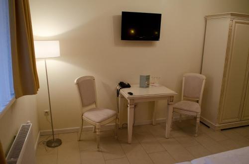 a room with a table and chairs and a tv on the wall at Hotel Pension Bellevue in Bad Doberan