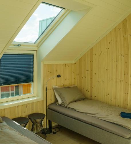 a bed in a room with a window at Lilleeideholmen Sjøhusutleie in Haug