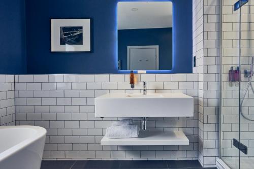 a bathroom with a white sink and blue walls at Malmaison Reading in Reading