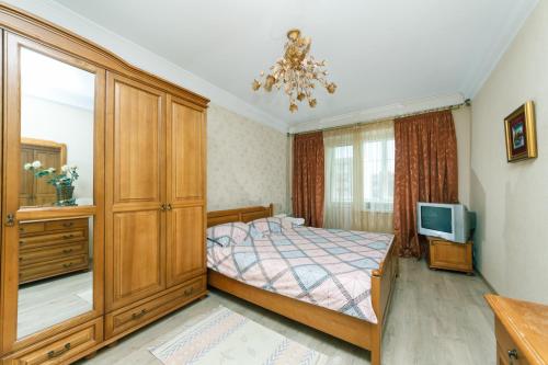 ein Schlafzimmer mit einem Bett, einer Kommode und einem TV in der Unterkunft Уютная квартира на Лукьяновке in Kiew