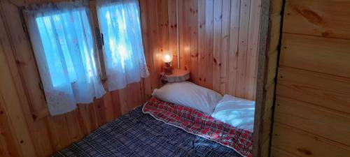 EUROPING VILLAGE MARSIA Abruzzo في Marsia: سرير صغير في غرفة خشبية مع نافذة