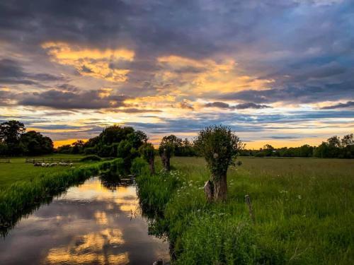 a river in the middle of a field at sunset at The Old Stables self catering in Salisbury