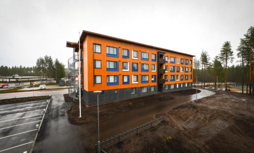 um edifício laranja no meio de um parque de estacionamento em Vuokatti Sport Apartments em Vuokatti