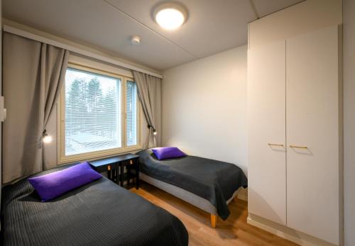 two beds in a room with purple pillows at Vuokatti Sport Apartments in Vuokatti