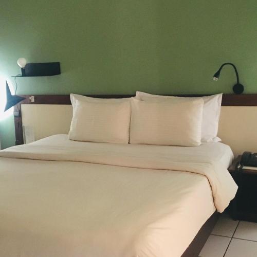 a bedroom with a white bed with a green wall at Ganalé Hôtel in Dakar