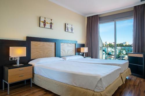 a bedroom with two beds and a large window at Pierre & Vacances Benalmádena Príncipe in Benalmádena