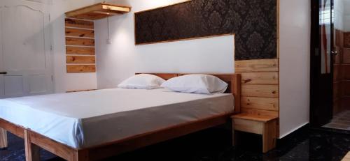 a bedroom with a large bed with a wooden headboard at Greenberg cottages Mararikulam in Mararikulam