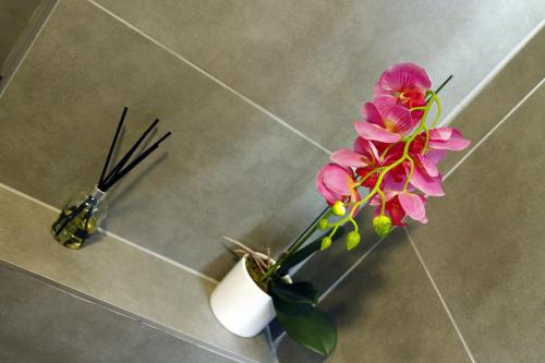 a pink flower in a vase on a tiled floor at The Guesthouse 6 on Vrede in Johannesburg